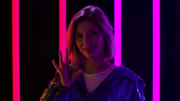 Portrait of a Young Stylish Woman Looking at the Camera Smiles and Shows Ok Gesture. Close Up. Slow alt