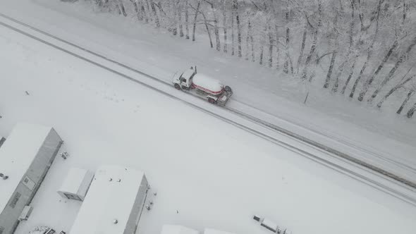 Top down view of truck driving along snow covered highway through a blizzard.