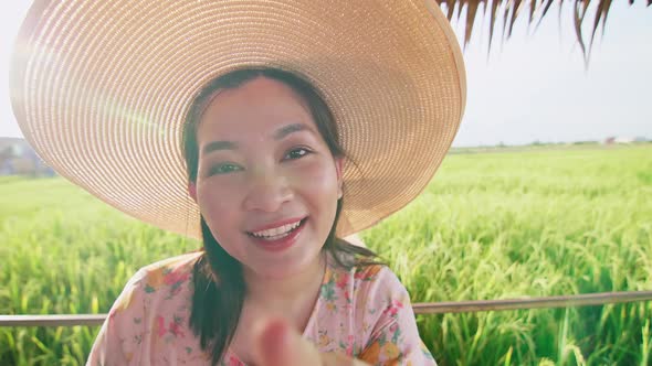 Asian Woman in hat on video call showing rice field with happy day in summer. alt