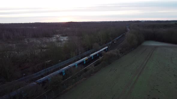 Drone footage of a train leaving the station  with a sunrise in the background. alt