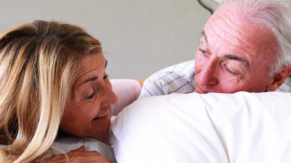 Happy senior couple interacting with each other on bed alt