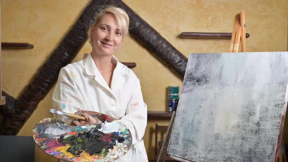 Satisfied Female Artist Posing Near New Picture Next to Easel alt