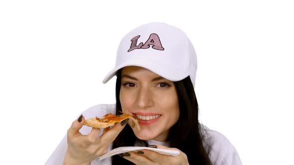 Cheerful Young Woman in Cap Eating and Enjoying Delicious Pizza alt