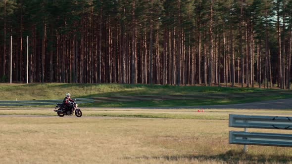 Motorcyclist on motorbike is practicing for race on asphalt road in forest. alt