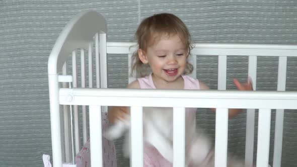 Little 2 Year Old Baby Girl in Crib Fun Throws Catches Soft Toys and Laughs