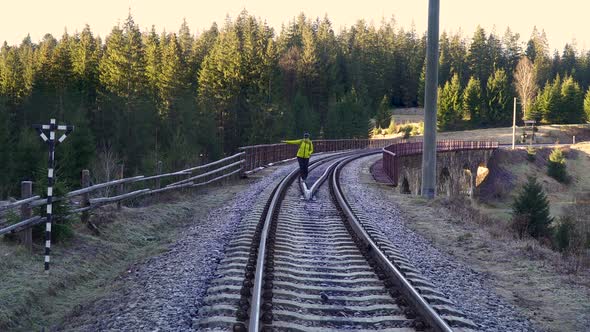 A Woman with a Backpack Walks on the Railway alt