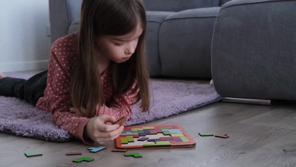 a Little Girl Lies on the Floor and Collects a Wooden Tetris Puzzle
