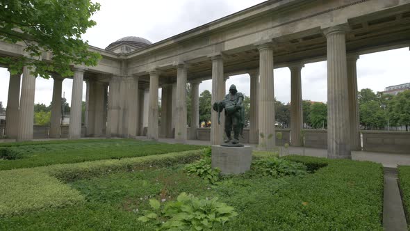 A statue near a colonnade in a garden