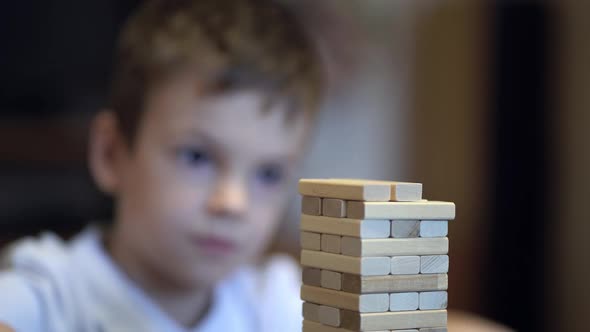Boy Playing in Board Game with Wooden Tower at Home alt