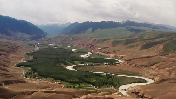 Mountain peaks and grassland are under white clouds alt