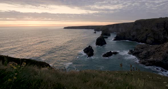 Aerial panoramic slow motion view of ocean waves against rock stacks in Cornw alt