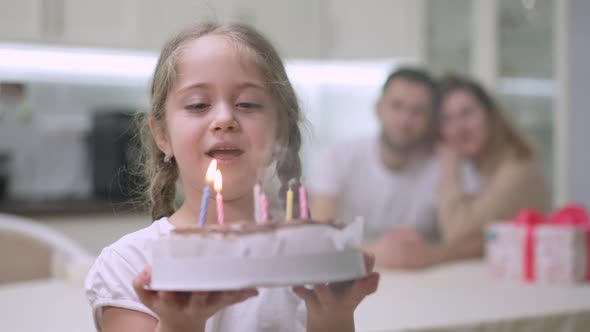 Cute Happy Caucasian Girl Making Wish and Blowing Candles on Birthday Cake Looking Back at Joyful alt