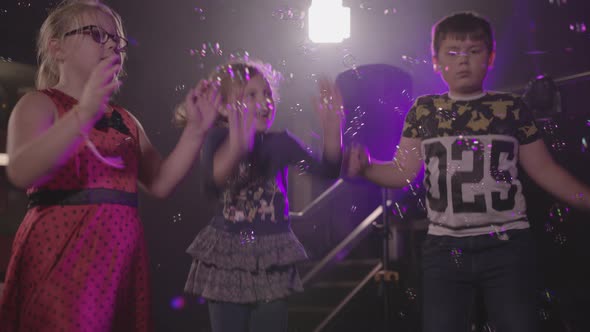 Kids Dancing at a Children's Party with Bubble Machine blowing Bubbles in to Air - Ungraded alt