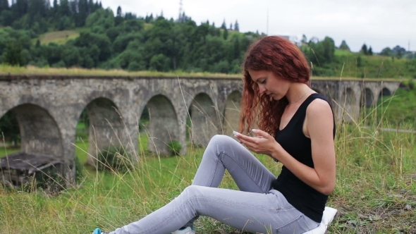 The Girl Writes Sms Sitting Near The Old Viaduct In The Mountains alt