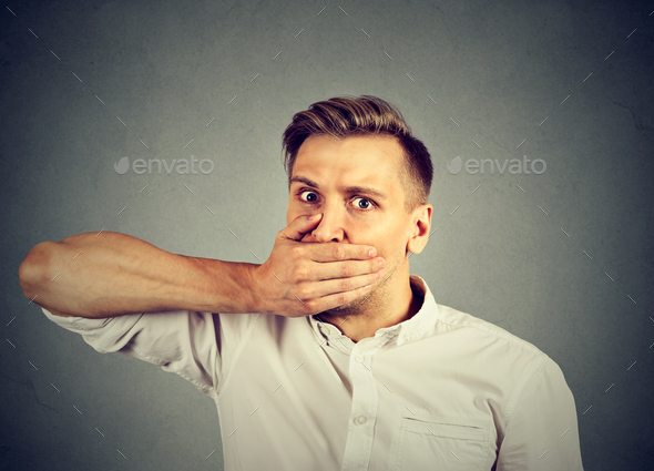 Scared young man covering mouth with hand