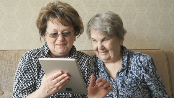 Two Women Watch Photos Using a Electronic Tablet