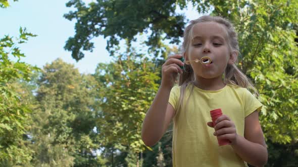 Cute Caucasian Girl Blowing Soap Bubbles in Park, Child Having Fun Outdoors