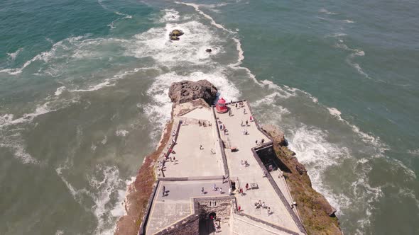 Aerial view tourists on Nazaré lighthouse descending reveal Atlantic Ocean horizon alt