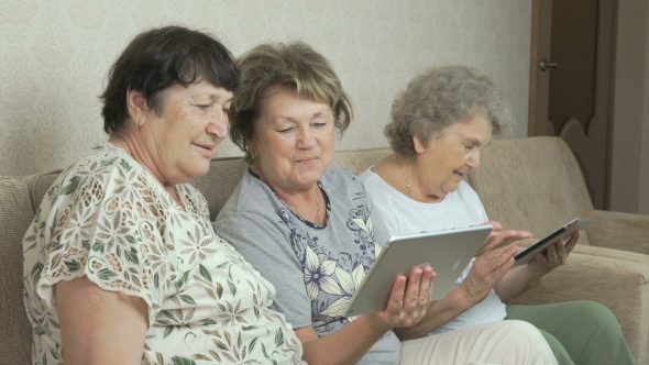 Grandmothers Look At Photos Using Digital Tablets