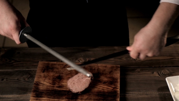 Midsection Of Male Chef Sharpening Knife In Commercial Kitchen alt