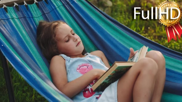 Young Curly Girl Reads a Book Lying in a Hammock