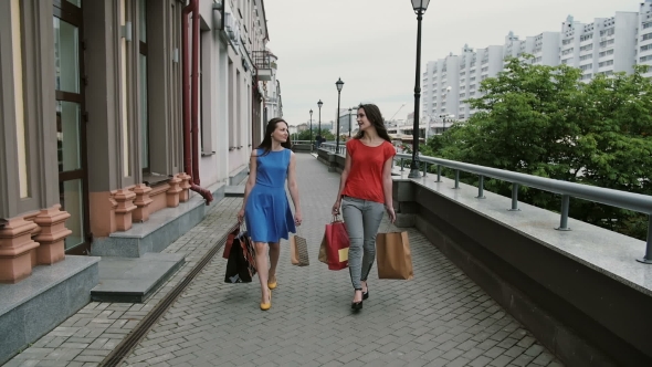 Happy Young Women Friends Walking With Shopping Bags, Talking Discuss Having Fun.  Stedicam Shot alt