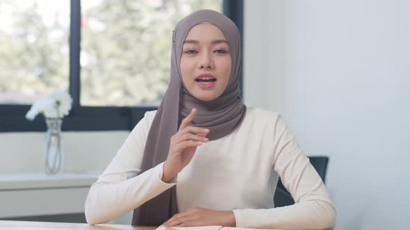 Asia muslim lady looking at camera talk to colleagues about plan in video call in new normal office. alt
