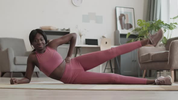 Sporty African-American Woman Exercising in Living Room alt