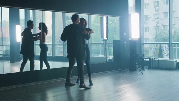 A Couple Practicing Dance Moves in Front of a Mirror Wall alt