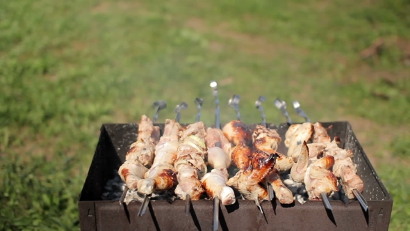 Chicken And Pork Grilled On Charcoal In a Barbecue. Meat Rotates And Has Golden Skin. Moving The