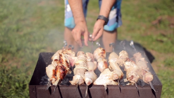 Chicken And Pork Grilled On Charcoal In a Barbecue. Meat Rotates And Has Golden Skin. Moving The