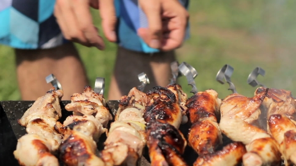 Chicken And Pork Grilled On Charcoal In a Barbecue. Meat Rotates And Has Golden Skin. Moving The