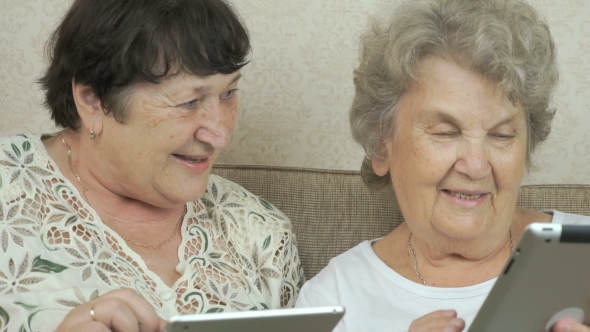 Two Elderly Sisters Holding Silver Digital Tablets