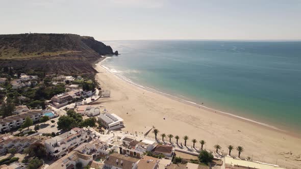 Wide Praia da Luz shoreline along vast horizon line on Algarve coast - Aerial alt