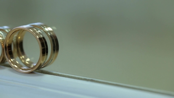 Two Bridal Golden Rings Stand On White Windowsill.