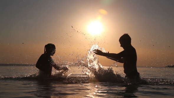 Children Spray Water At Sunset