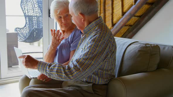 Side view of Caucasian senior couple using laptop at comfortable home 4k alt