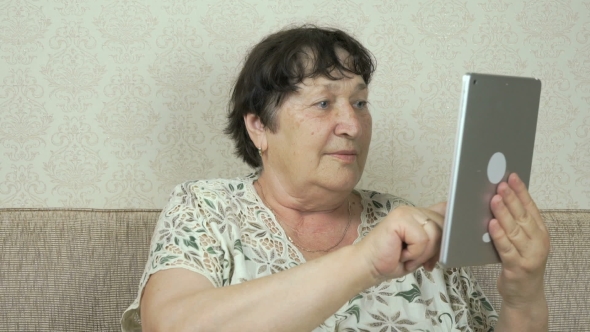 Elderly Woman Holding a Silver Digital Tablet