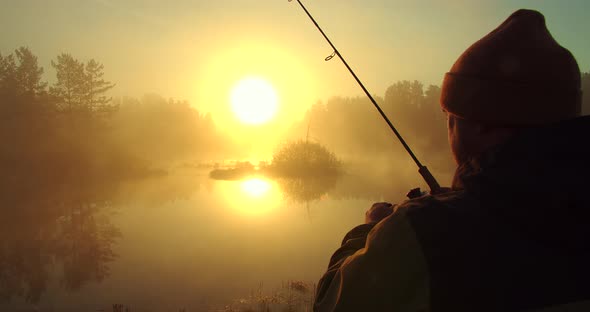 Unrecognizable Man Fishing in Lake at Dawn