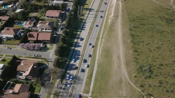Aerial Drone shot of highway with cars going through and suburbs on side, tilting down alt