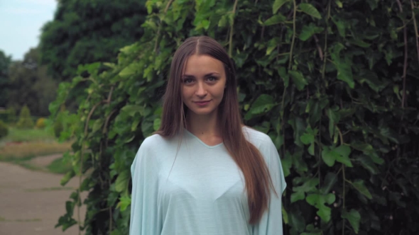 A Young Girl Stands Under a Green Tree And Wondering News. alt