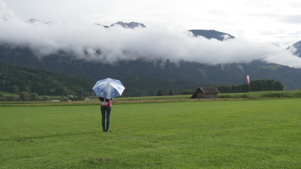 Young Woman With Umbrella Standing And Walking On Grass