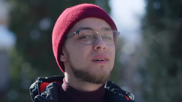 Closeup of Smiling Young Handsome Caucasian Man Exhaling Warm Breathe on Frosty Winter Day Outdoors alt