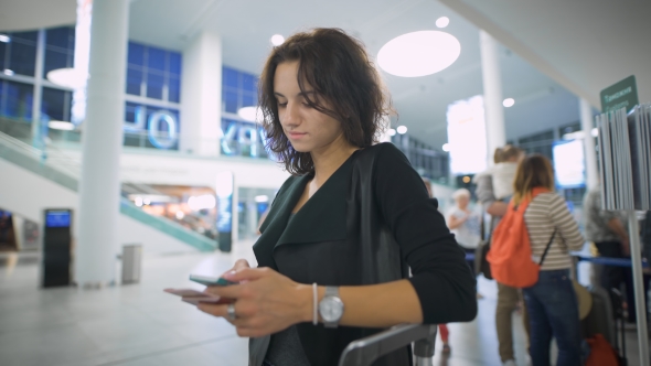 A Young Lady Is Thinking About Her Trip Holding Her Smartphone alt