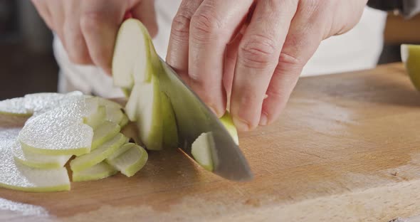 Close up of a chef knife slicing a green apple alt