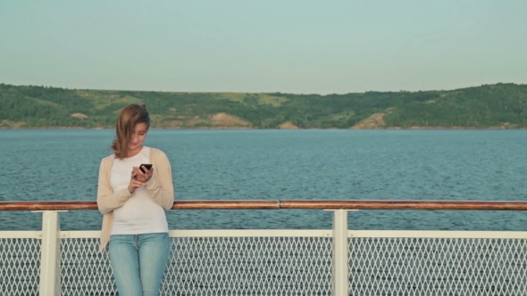 Woman Using Mobile Phone On Deck Of Cruise Ship