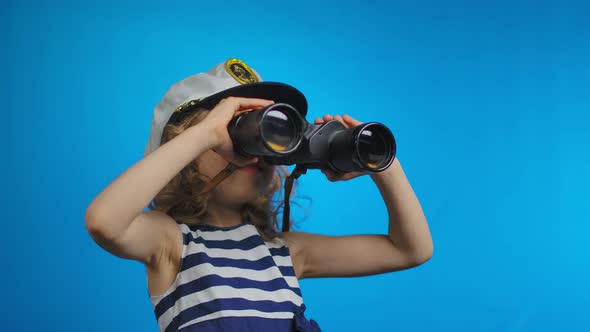 Little Blond Girl in Sailor Hat is Looking at the Sky Through the Binoculars alt