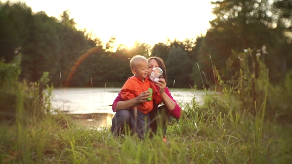 Pretty Young Mother With Her Little Son Happily Blow Bubbles At Sunset alt