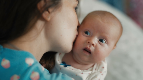 Mother Holding Her Newborn Baby In Her Arms And Gently Kissing His Cheek. alt