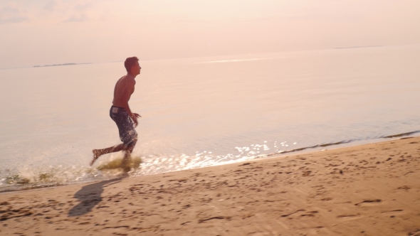 Teen Boy Is Running On The Beach, Raises Splashes alt